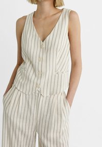 Pruhovaná lněná vesta v béžové a šedé barvě, s hlubokým výstřihem do V, pěti knoflíky a dvěma bočními kapsami, s přiléhavým střihem a hladkou texturou.