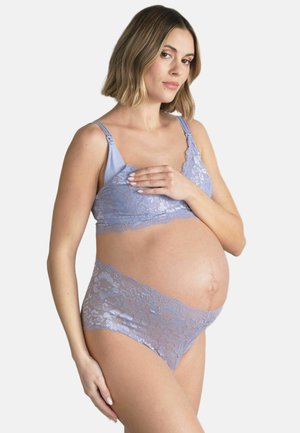 Gravid kvinde iført lyslilla blonde amme-bh og matchende undertøj, der blidt holder sin mave med den ene hånd.