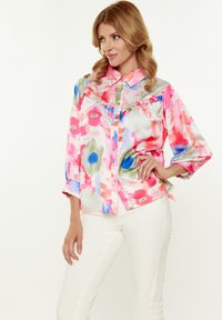 Bunte Blumenbluse aus weichem, leichtem Satin mit Rüschen an der Vorderseite. Verfügt über ein Knopfverschluss-Design und lange Ärmel.