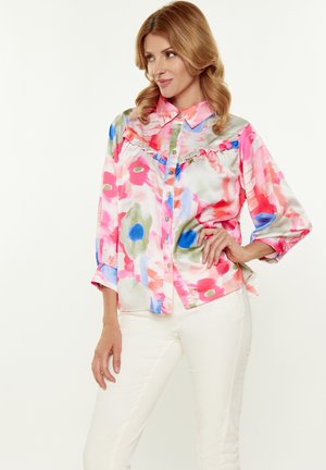 Blusa floreale colorata in satin morbido e leggero, con rouches lungo la parte anteriore. Presenta un design con bottoni e maniche lunghe.