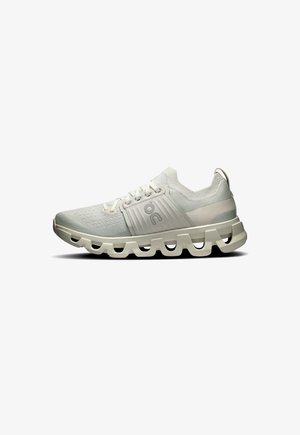 Chaussure de sport gris clair avec un dessus texturé, un col rembourré et une semelle intermédiaire épaisse et creuse pour un meilleur amorti. Présente des accents tonaux.