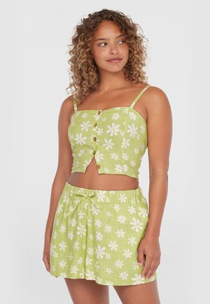 Top corto floral verde y falda a juego, con margaritas blancas, cierre de botones, tirantes ajustables y cintura con cordón.