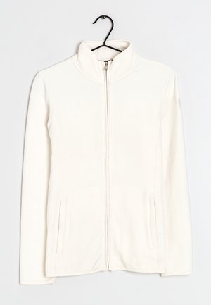 Veste polaire blanche avec fermeture éclair intégrale et col montant, suspendue à un cintre noir sur un fond uni.