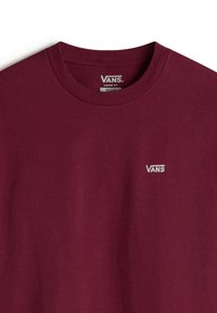 T-shirt en coton bourgogne avec un col rond et une coupe ample. Présente un logo "VANS" brodé en blanc sur la poitrine gauche.