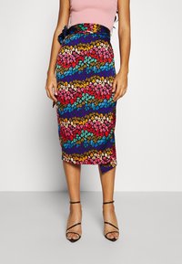 Jupe crayon à imprimé léopard coloré avec un ourlet qui descend légèrement à l'arrière, dotée d'un nœud noir à la taille et d'un tissu léger.