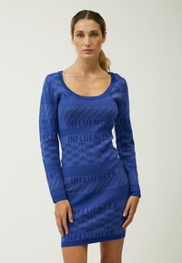 Blaues Langarmkleid mit auffälligem "INFLUENCER"-Textmuster, tailliertem Schnitt und strukturierter Oberfläche mit gerippten Details.