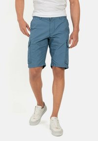 Lyseblå cargo shorts med sidelommer og flad front, lavet af letvægtsstof, parret med hvide sneakers.