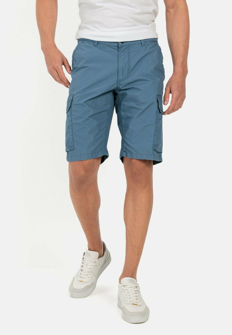Lyseblå cargo shorts med sidelommer og flad front, lavet af letvægtsstof, parret med hvide sneakers.