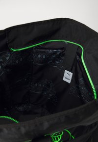 Czarna torba wewnątrz z zielonym zamkiem, teksturowana podszewka z grafikami kotów oraz metką z napisem "PUMA RIPNDIP."