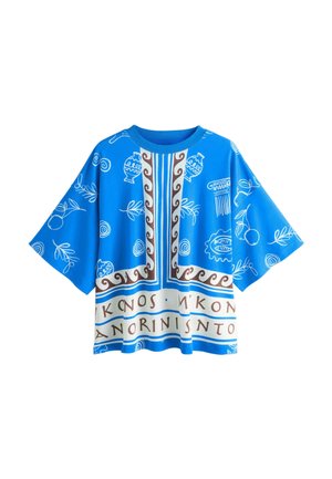 Blå oversized T-shirt med hvide græsk-inspirerede mønstre, brun dekorativ kant og antikke græske bogstaver langs nederste kant.