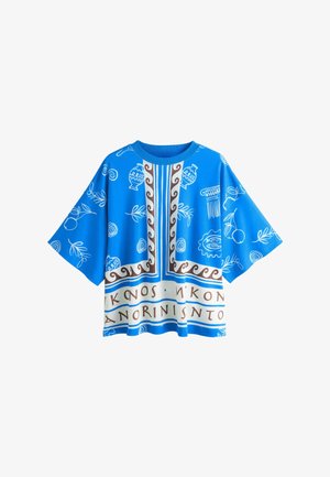 Niebieska, luźna koszulka z białymi wzorami inspirowanymi Grecją, brązową dekoracyjną bordiurą oraz napisami w stylu starożytnej Grecji na dolnym brzegu.