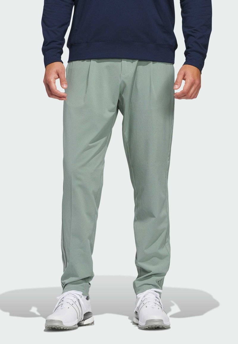 Light green athletic pants with a textured pattern, featuring a loose fit and tapered legs, paired with white athletic shoes.