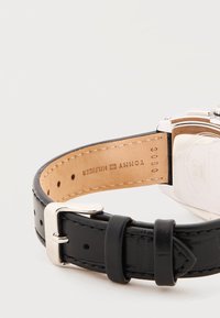 Μαύρο δερμάτινο λουράκι ρολογιού με ασημένια αγκράφα, λεπτομέρειες ραφής και λογότυπο Tommy Hilfiger στη μαύρη εσωτερική πλευρά της λωρίδας.