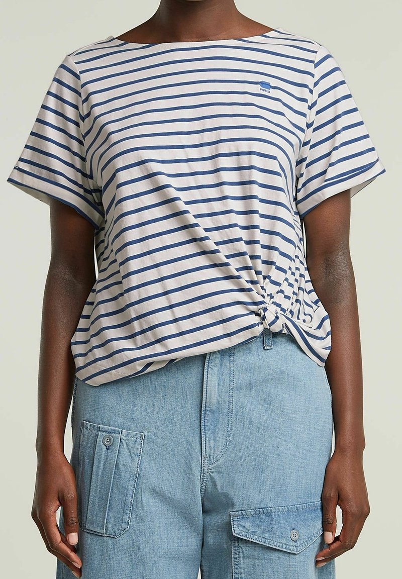 Top de manga corta a rayas en crema claro con rayas horizontales en azul marino; cuenta con un detalle de nudo en el costado y un ajuste relajado.