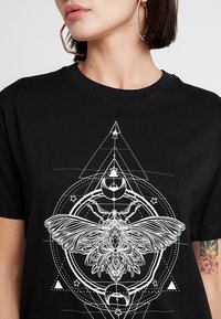 Czarny bawełniany t-shirt z dużym białym grafiką przedstawiającą ćmę otoczoną geometrycznymi kształtami i elementami kosmicznymi.