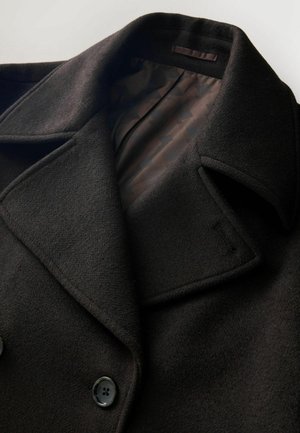 Juodas vilnonis paltas su dideliais atvartais, dvigubu sagčių uždarymu ir lygiu raštuotu vidiniu pamušalu. Textūruota, minkšta medžiaga.