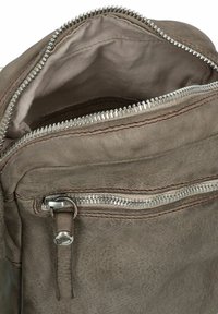 Borsa a zip in pelle grigia con zip metalliche argento, caratterizzata da una texture liscia e cuciture a contrasto. L'apertura superiore rivela un interno foderato in tessuto.