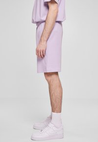 Lyse lavendel bomullsshorts med elastisk midjebånd, sidelommer og en avslappet passform, kombinert med hvite joggesko og crew-sokker.