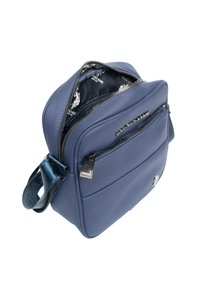 Granatowa torba na ramię wykonana z teksturowanego materiału, z wieloma zamykanymi na zamek kieszeniami i lśniącym paskiem. Wnętrze wyściełane wzorem logo.