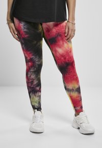 Fargerike tights med et tie-dye-mønster i røde, gule og svarte nyanser. Laget av elastisk stoff, tilpasset designet forbedrer bevegelighet.