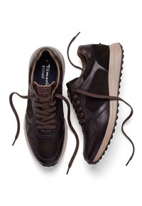 Paire de baskets en cuir et daim marron foncé avec semelles beiges et lacets lâches, vues de dessus sur fond blanc.