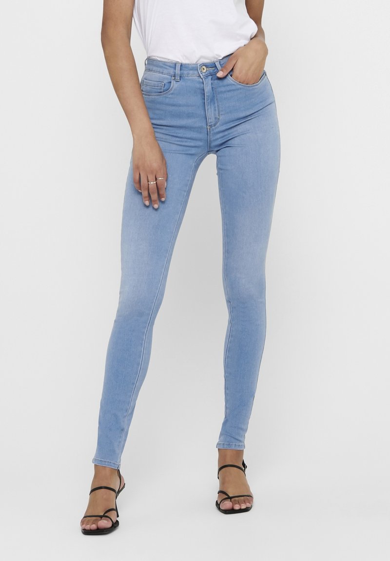 Jeans skinny de tiro alto en azul claro, confeccionados en denim. Cuenta con cinco bolsillos, cierre de cremallera y botón, con una silueta ajustada y ligero estiramiento.