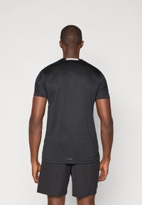 Black athletic shirt made of a smooth, lightweight material. Features short sleeves, a crew neck, and a small logo at the hem.