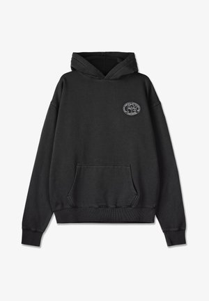 Czarna bluza z kapturem, oversize, z miękkiego materiału, z przednią kieszenią kangurką, ściągaczami przy rękawach i u dołu, z okrągłym graficznym logo na klatce piersiowej.