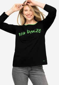 Zwarte langemouwen top met "zeebries" in groene letters, ronde halslijn met groene bies, gemaakt van een zachte stof.