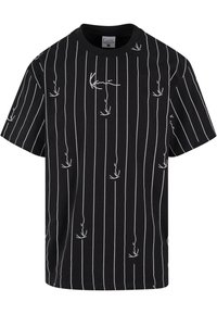 Black cotton t-shirt featuring vertical white stripes and small white bird designs. Classic crew neck and short sleeves. Relaxed fit.