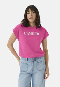 Pink cotton t-shirt with short sleeves, featuring the word "L'AMOUR" in white print across the front, paired with light blue jeans.