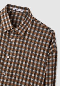 Camicia a quadri marrone e nera in tessuto, con colletto classico e chiusure a bottoni bianchi, caratterizzata da una texture morbida e un design leggero.