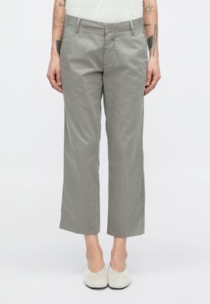 Pantalon court gris en mélange de coton avec une coupe droite, doté d'une fermeture éclair, de poches avant et d'une texture lisse. Les chaussures assorties sont de couleur claire.