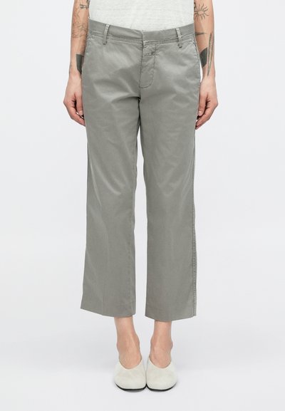 Graue, kurze Hose aus Baumwollmischung mit geradem Schnitt, ausgestattet mit Reißverschluss, Vordertaschen und glatter Textur. Kombiniert mit hellfarbigen Schuhen.