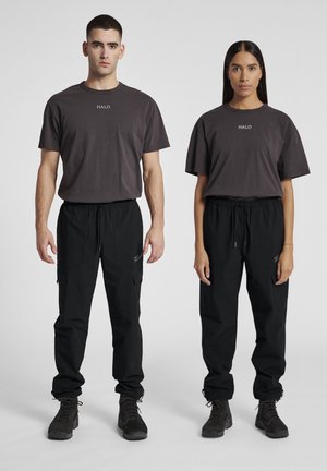 Two individuals wear matching dark gray t-shirts with "HALO" printed in white, paired with black cargo pants and rugged black boots.