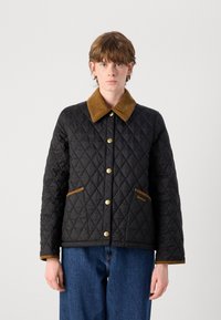 Jachetă neagră matlasată cu model în diamant, guler din corduroy maro și accente pe buzunare, nasturi aurii cu prindere tip snap și o croială ușor structurată.