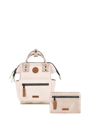 Light pink backpack with front zipper pocket and matching small pouch, both featuring brown leather zipper pulls and Cabaia logo patches.