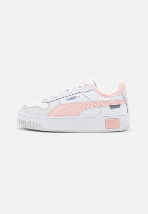 Baskets Puma blanches et rose clair avec lacets à l'avant, semelle épaisse et logo de marque sur le côté et le talon, présentées de profil sur fond blanc.