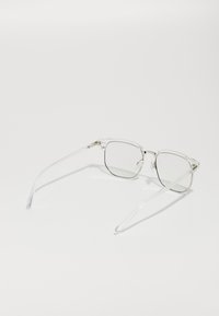 Clear, rectangular eyeglasses with thin, transparent frames and silver metal accents. Lenses have a light tint, enhancing visual clarity.