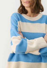 Gestreifter Pullover in Blau- und Cremetönen, mit gestrickter Textur, weitem Rundhalsausschnitt und langen Ärmeln. Bequeme und lockere Passform.