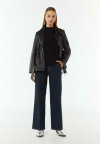 Black leather biker jacket over a black sweater, paired with dark wide-leg jeans and silver ankle boots. Simple, layered design with textures.