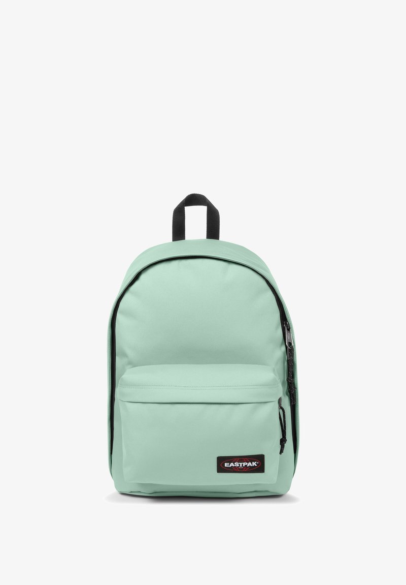 Mochila verde menta claro hecha de tela duradera, con un bolsillo frontal con cremallera, correas acolchadas y un asa en la parte superior. Parche negro con el logotipo exhibido.