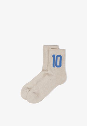 Paar beige Kniestrümpfe mit blau gestrickter Nummer 10 an der Außenseite nahe der oberen Bündchenkante.