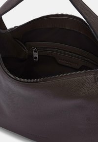 Borsa in pelle marrone con finitura testurizzata, dotata di una tasca con zip e di un rivestimento interno liscio. Design minimalista con branding discreto.