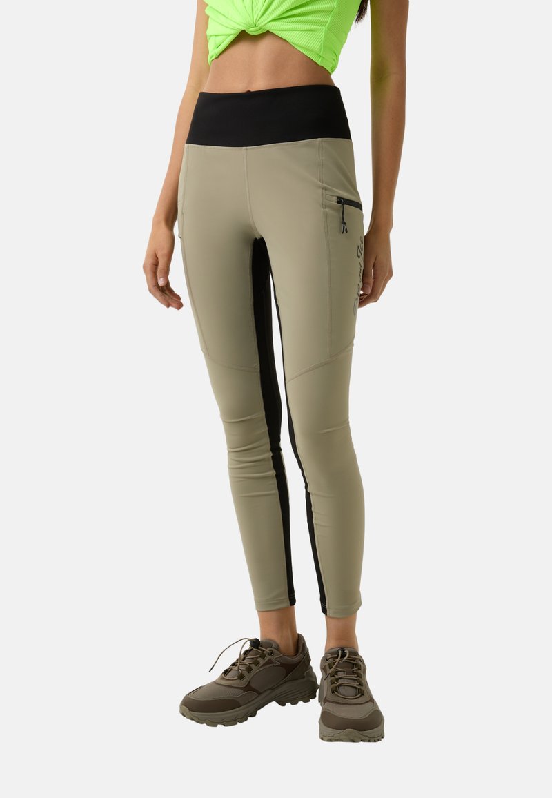 Compression leggings in light olive green with black side panels, high waist, zip pocket, and smooth fabric texture.