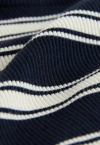 Látka v námořnické modré a krémové barvě se pruhy, která má vroubkovanou strukturu. Pruhy se střídají v šířce, čímž vytvářejí kontrastní vzor. Měkký materiál.