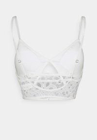 Bralette branco em renda com alças ajustáveis, parte superior em algodão suave e uma delicada seção inferior em renda floral, com um recorte decorativo nas costas.