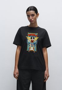 Camiseta de algodón negra con un gráfico colorido de Wonder Woman y el texto "WW84", sobre un diseño azul y amarillo con acentos de estrellas.