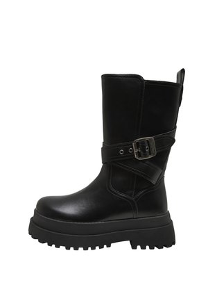 Botte en cuir noire mi-mollet avec semelle épaisse à crampons et sangle ajustable avec boucle métallique autour de la cheville.