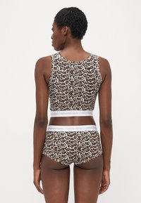 Sportová podprsenka s leopardím vzorom a zodpovedajúce hipster nohavičky vyrobené z mäkkej textílie, s bielym brandingom na páse a priliehavým strihom.